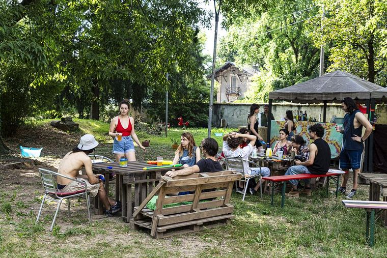 Persone ai tavoli tra gli alberi del parco al Livore Beach Party